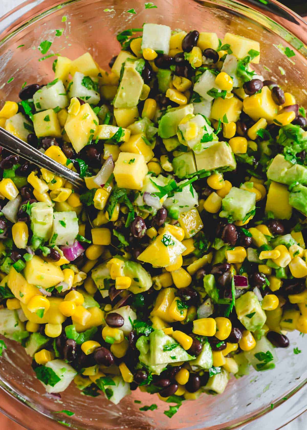 Mango black bean salad in a large bowl with spoon.