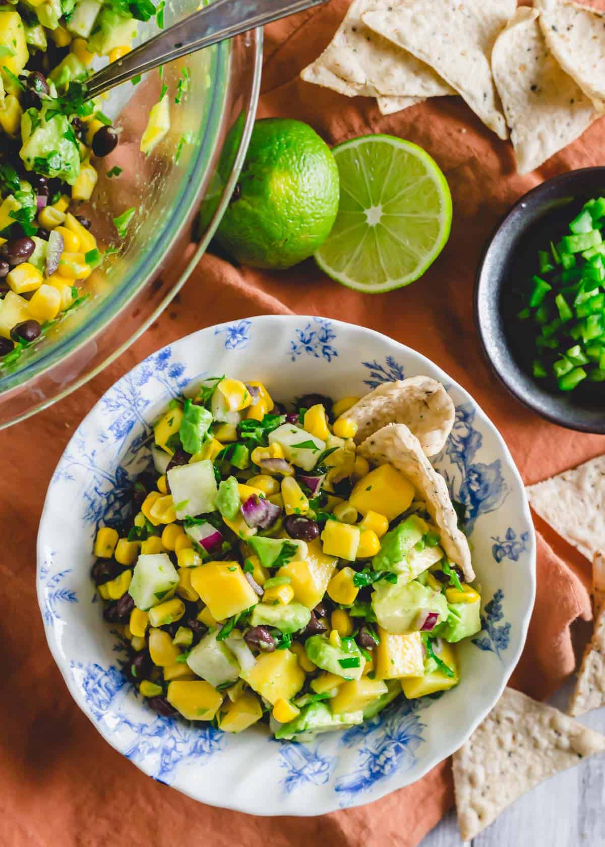 Mango black bean salad recipe in a small bowl with tortilla chips.
