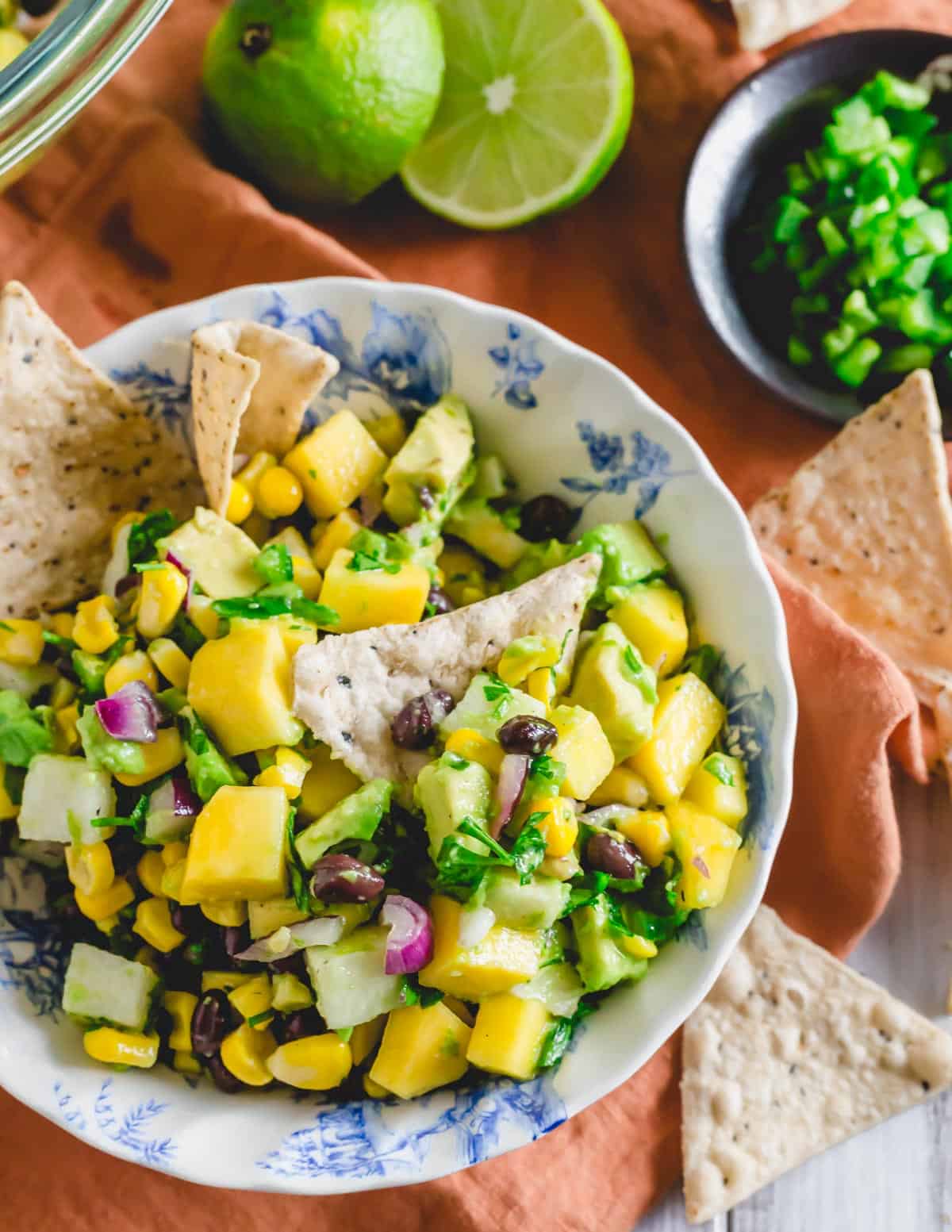 Tortilla chip with mango black bean salad in a bowl.