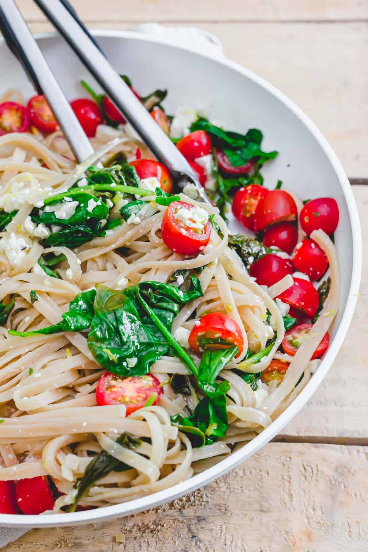 Linguine with spinach, lemon, feta and cherry tomatoes in a skillet.