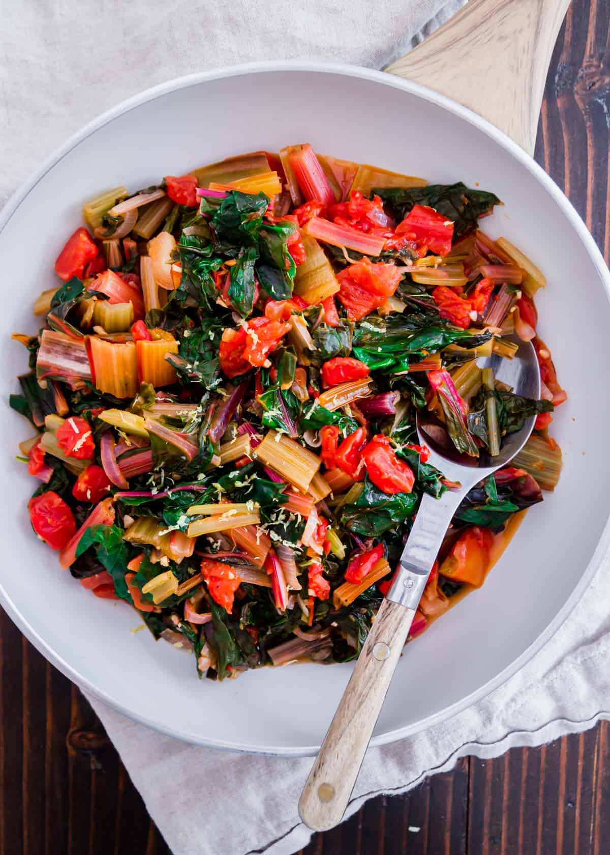 A simple recipe for sautéed Swiss chard with garlic, onions, tomatoes and lemon. Garnished with some optional fresh parmesan cheese and easily made in a pot or skillet. It's a low-calorie, vegetarian healthy side dish packed with all the nutrients from fresh leafy greens.