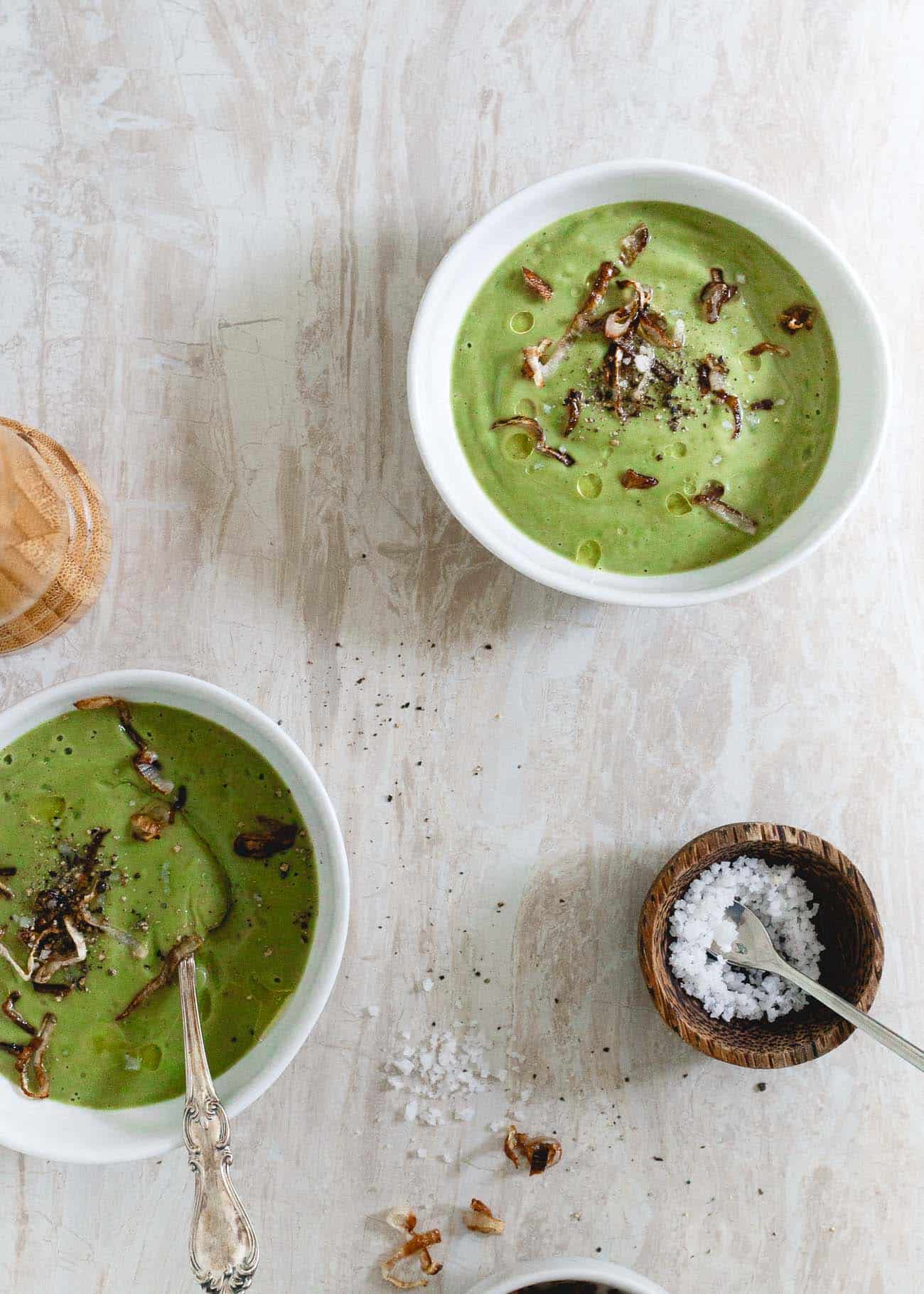 Two bowls of simple vegan broccoli soup next to a ramekin of salt.