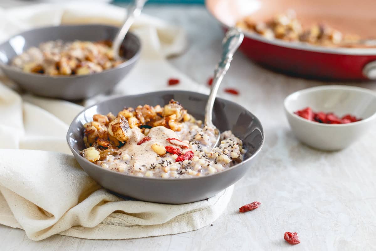 Warm quinoa cereal is topped with almond butter, caramelized banana walnut compote and some goji berries for a healthy and satisfying breakfast.