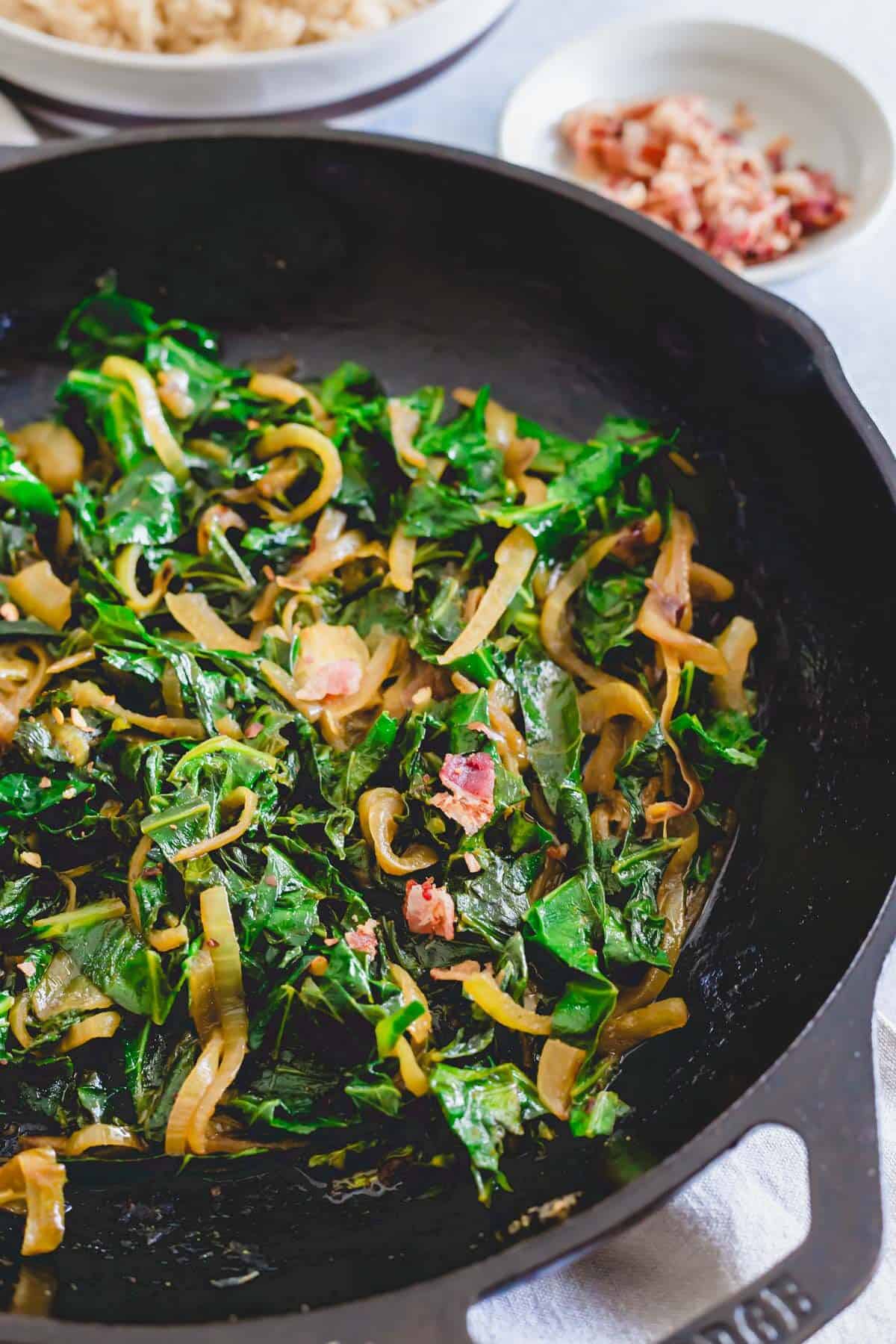 Cooked spicy collards with onions, spices and bacon in a cast iron skillet.
