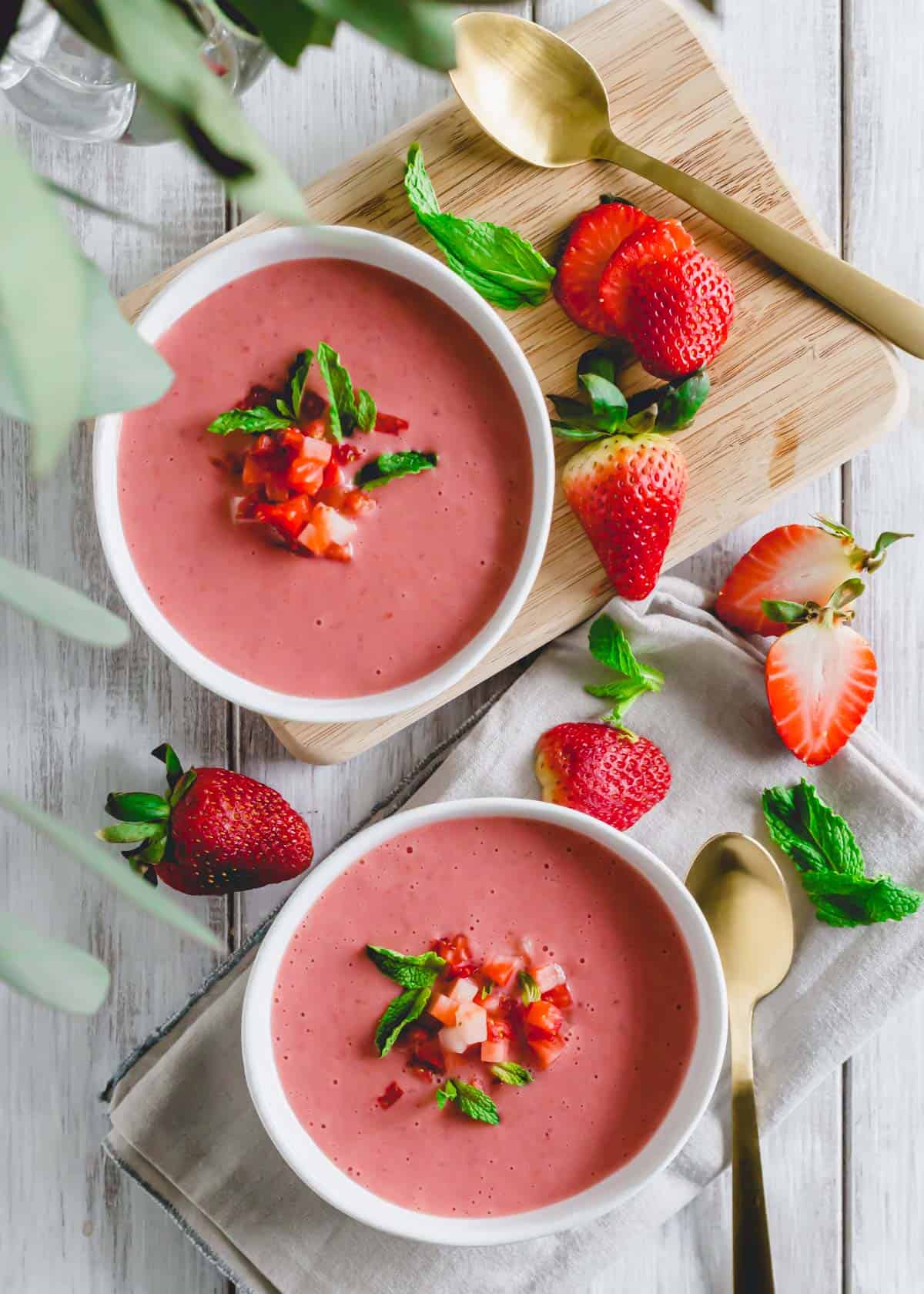 Chilled strawberry soup garnished with mint leaves and chopped strawberries.