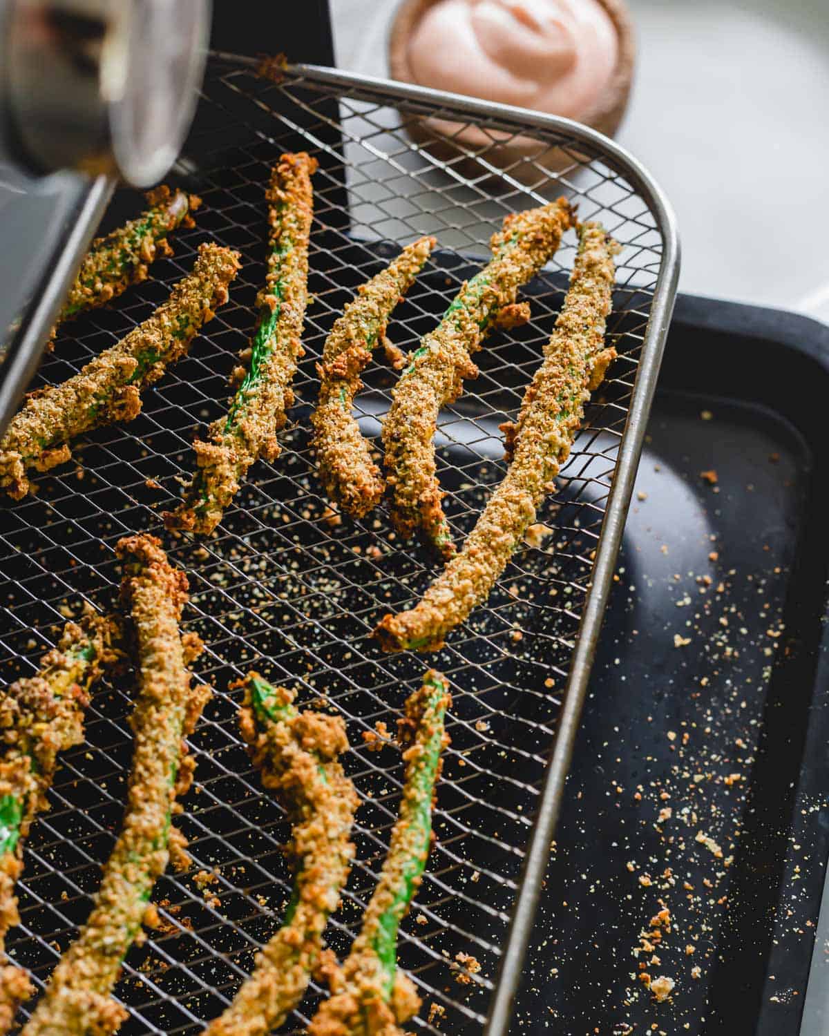 Green bean fries on a tray in an air fryer.