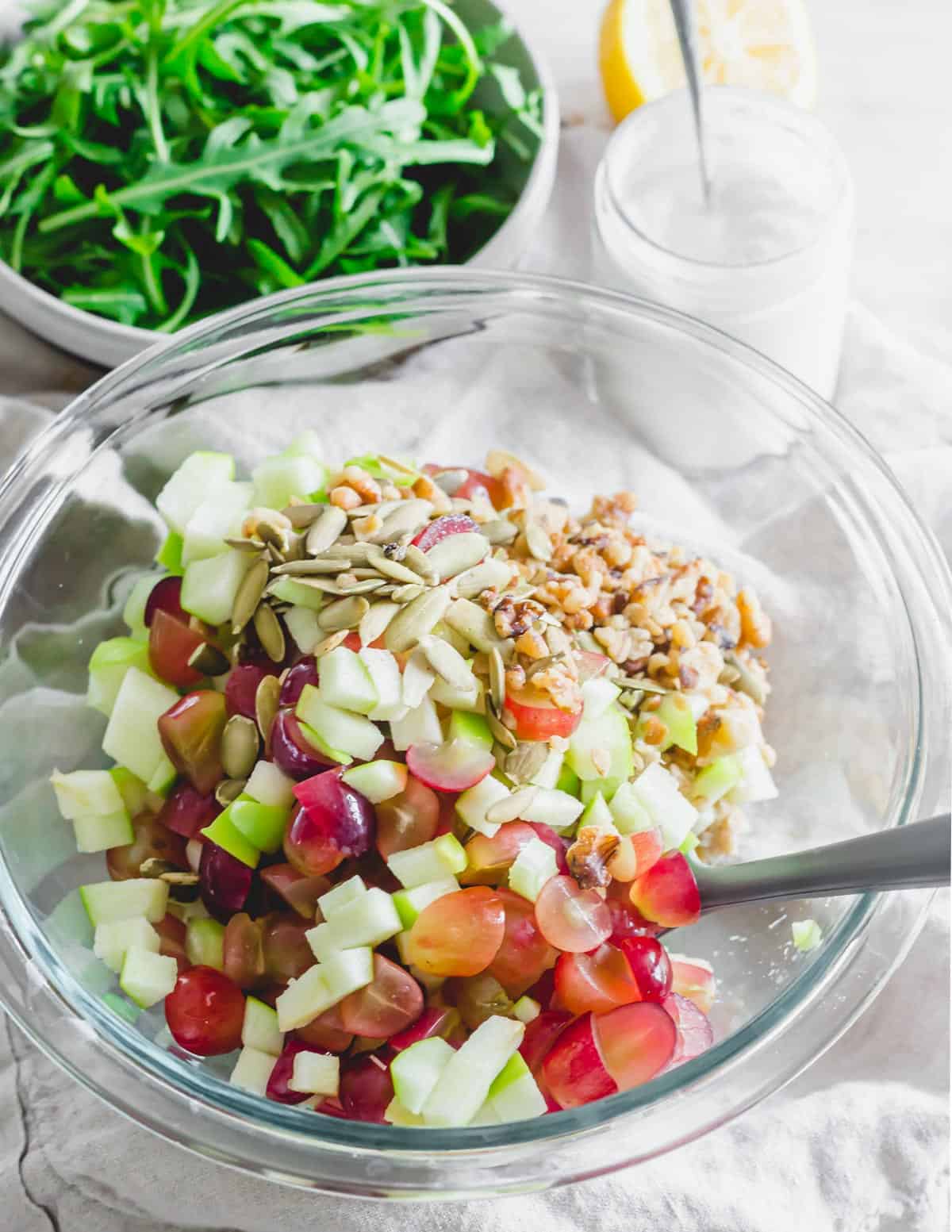 Tuna Waldorf salad ingredients in a glass mixing bowl with a spatula.