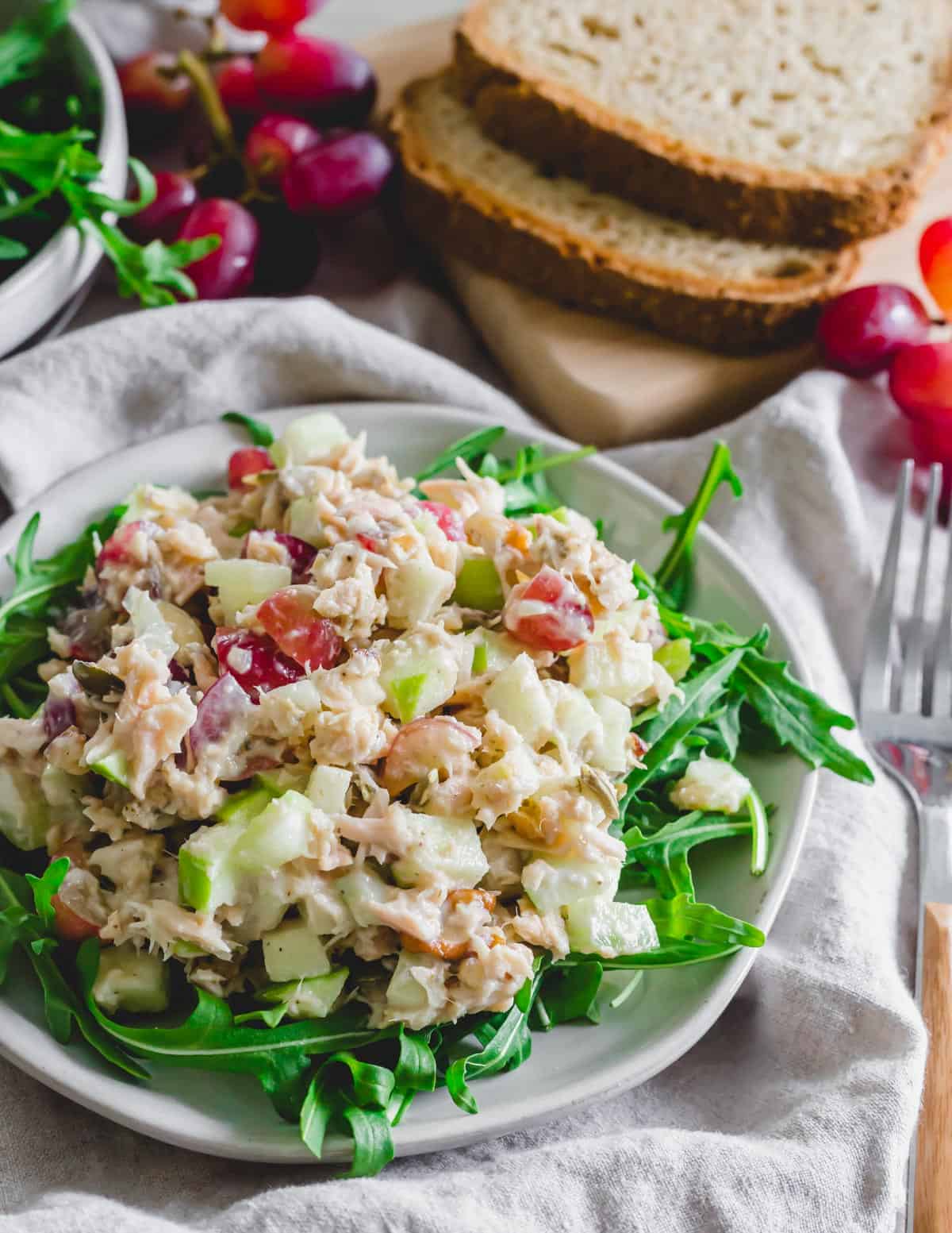 Tuna Waldorf Salad on a bed of arugula on a plate.