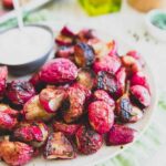 Roasted radishes on a white plate with dipping sauce.