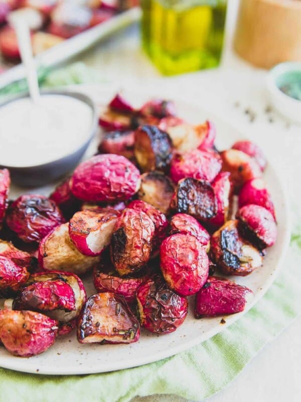 Roasted radishes on a white plate with dipping sauce.
