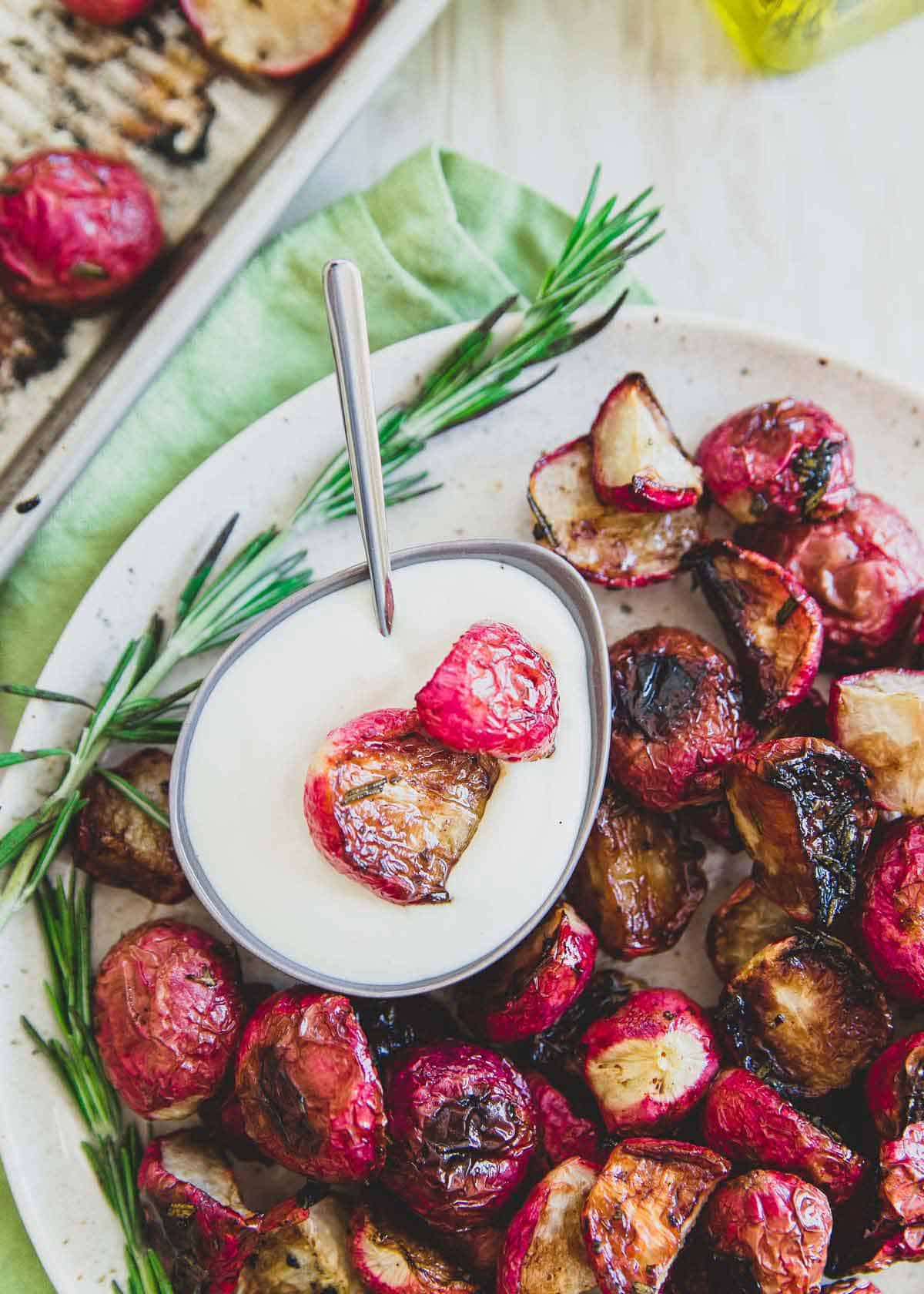 A simple Greek yogurt dipping sauce is the perfect pairing to these crispy rosemary oven roasted radishes.