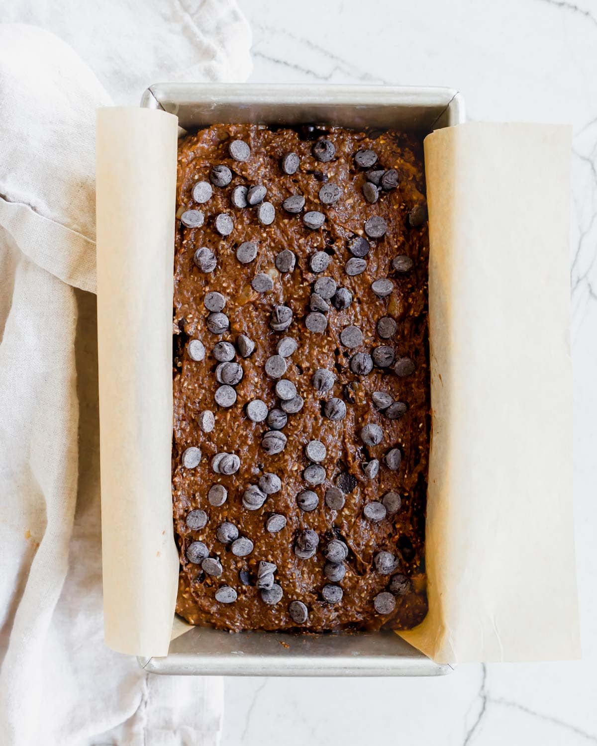 Chocolate banana bread batter in a parchment lined loaf pan.