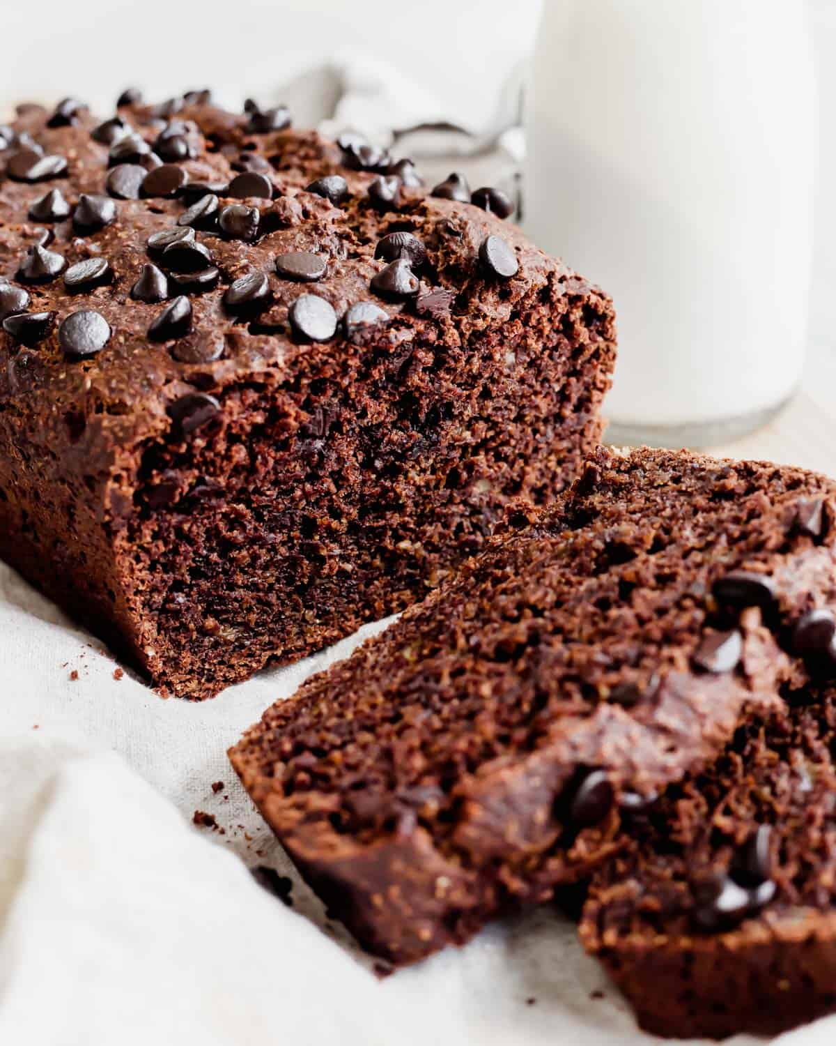 Close up of double chocolate banana bread sliced on a cutting board with milk in the background.