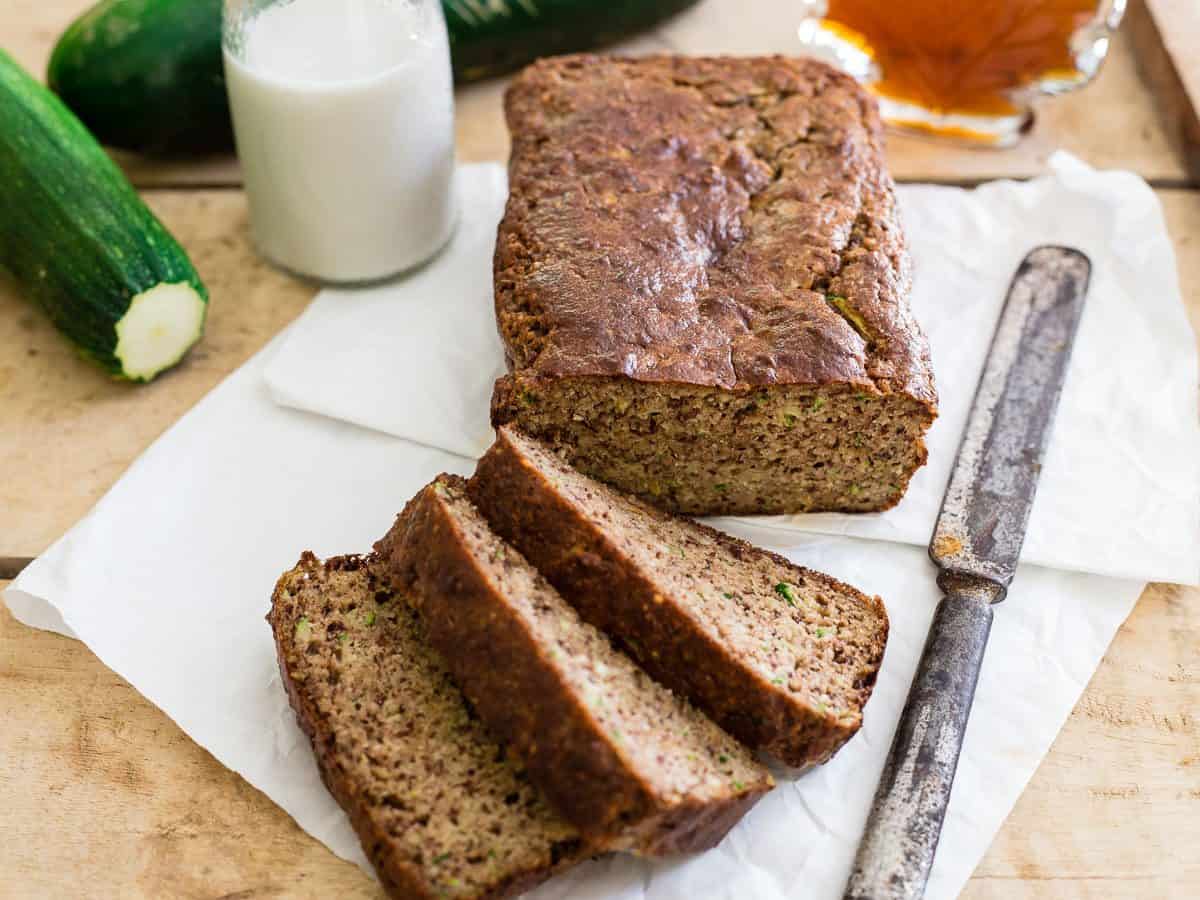 Paleo almond zucchini bread on parchment paper, sliced with a knife on the side.