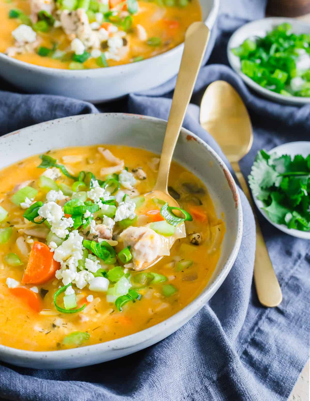 Buffalo chicken soup with orzo in a serving bowl with spoon.