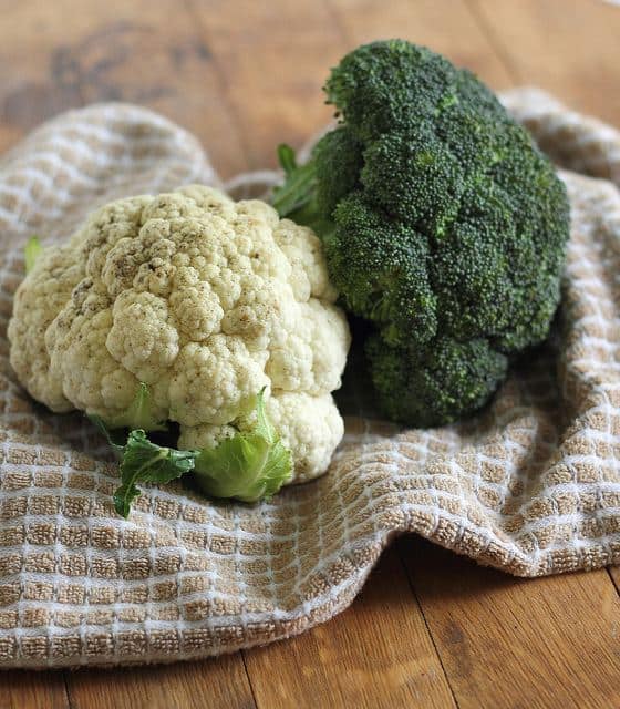 A head of broccoli and cauliflower on a dish towel.