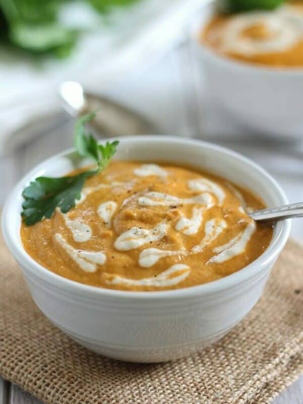 A bowl of carrot soup with a spoon on top.
