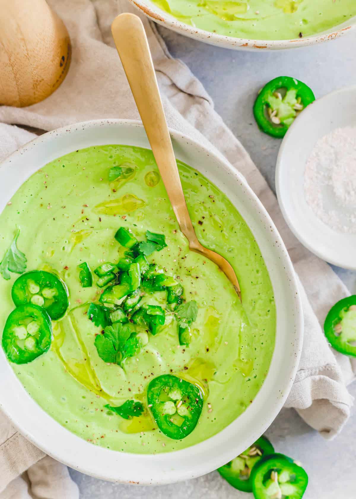 Cold creamy avocado soup in a bowl with a spoon.