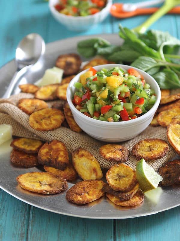 Baked plantain chips with a bowl of tropical salsa in the middle.