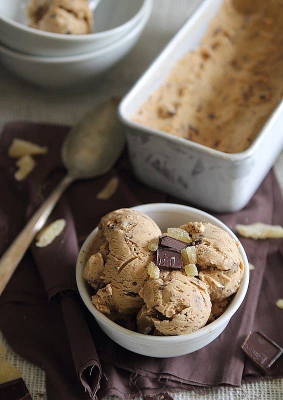 several scoops of gingerbread ice cream in a white bowl with chocolate and ginger chunks on top