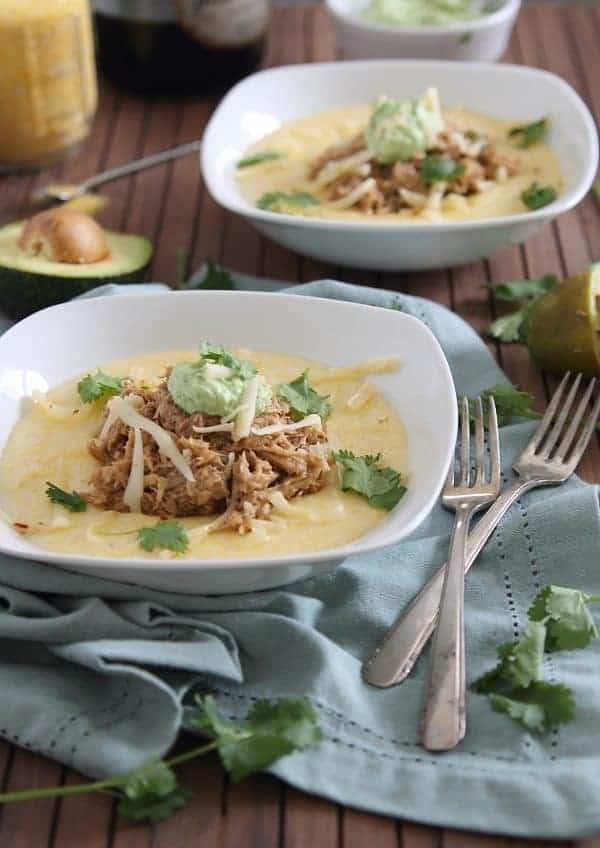 This slow cooker balsamic pulled pork is sweet and juicy served over cheesy polenta and topped with a cilantro infused avocado crema. Serious comfort food!