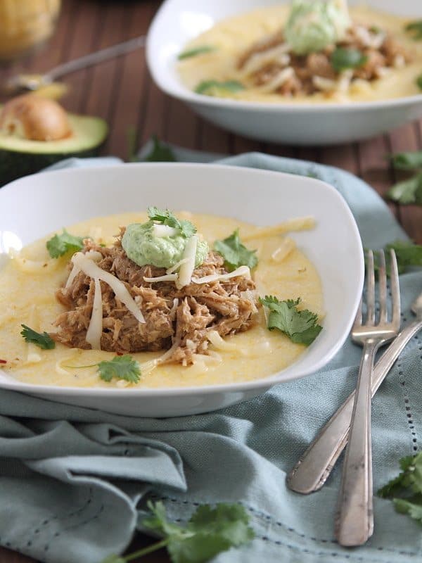 This slow cooker balsamic pulled pork is served over cheesy polenta and topped with a cilantro infused avocado crema. Serious comfort food!