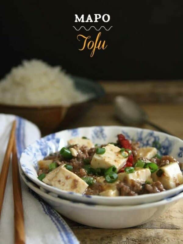 A bowl of tofu with chopsticks and a bowl of rice.