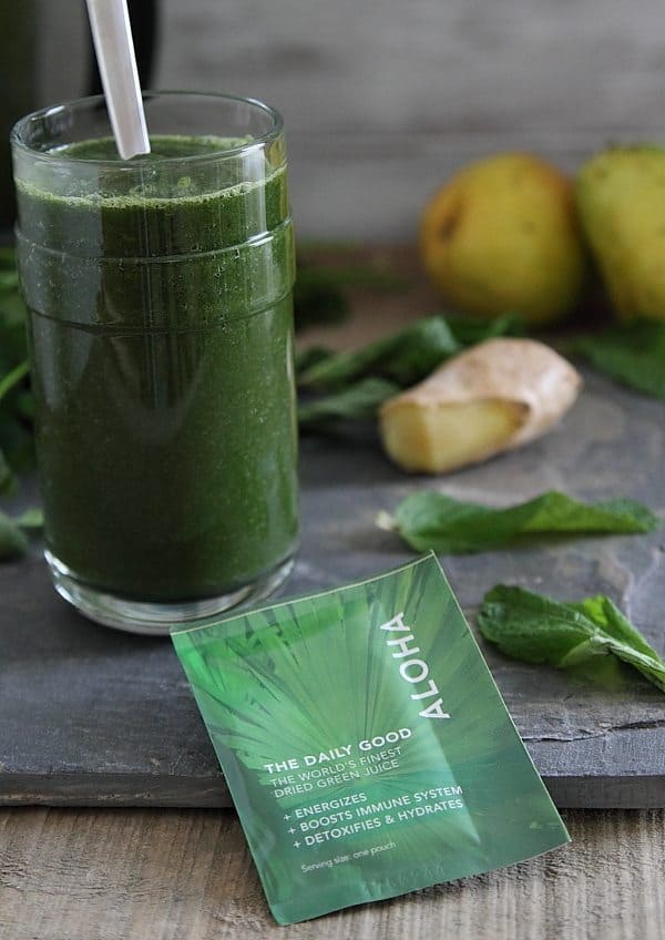 Green Detox Smoothie in a glass with a straw next to a packet of superfood powder.