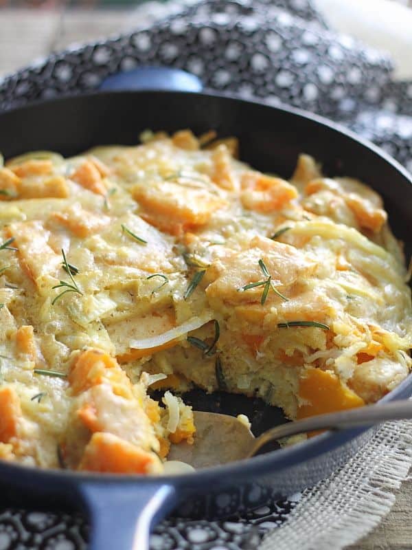 Rosemary butternut squash pie in a cast iron skillet with a spoon.