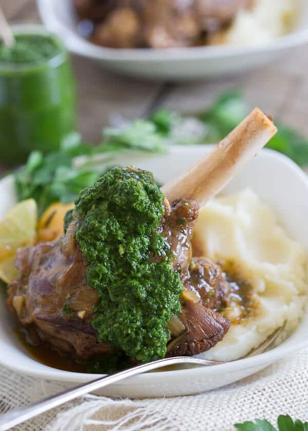 These citrus braised lamb shanks are served with a spicy green harissa. They're cooked until falling off the bone tender and served with the sweet and tangy citrus juices.