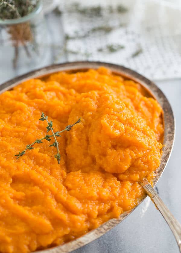 Scooping out a spoonful of parsnip and carrot puree from a serving dish.