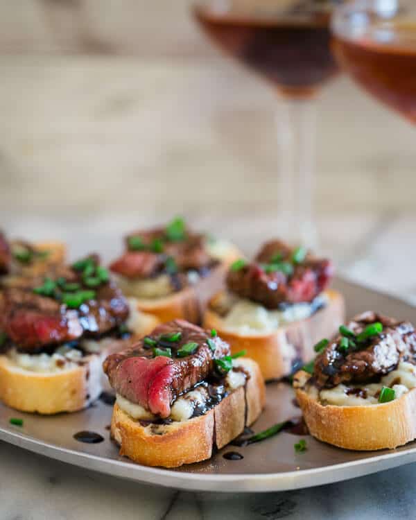 These blue cheese steak crostini are the perfect little appetizer bite. Garlicky toasted bread topped with salty blue cheese, rare steak and a balsamic reduction are a great Valentine's Day nibble.