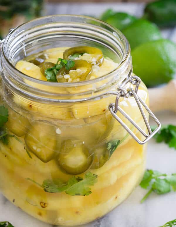 Pickled pineapple with jalapeños in glass jar.