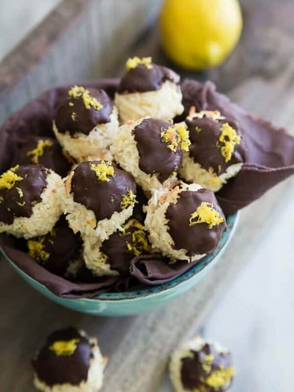 A bowl of chocolate covered coconut cookies with lemons.