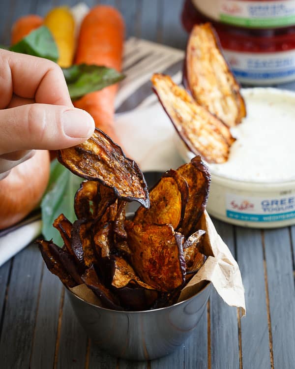 A small ramekin filled with crispy eggplant chips with others in the background.