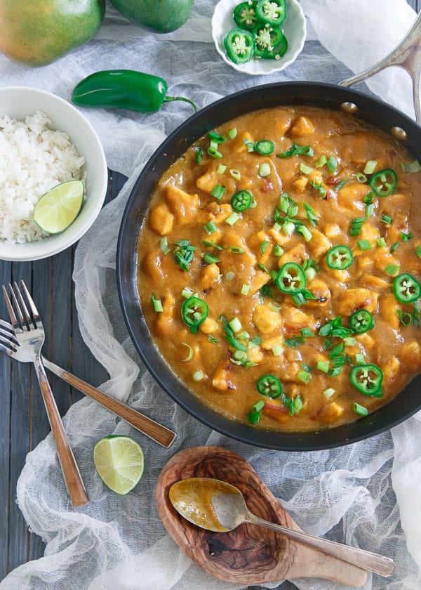 Spicy mango chicken meal in a skillet next to a bowl of rice.