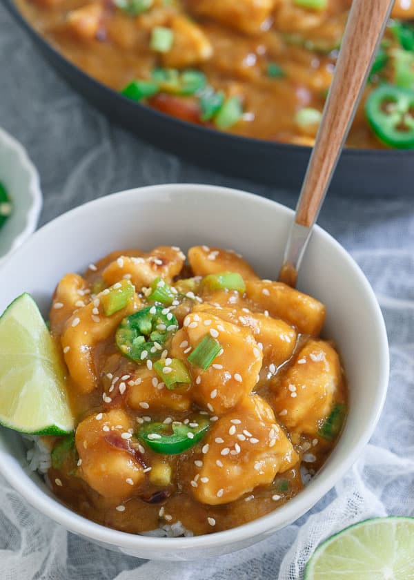 Jalapeño mango chicken in a bowl over rice with a lime wedge.