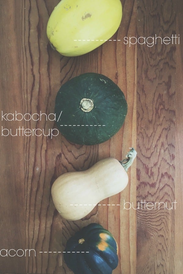 Acorn, butternut, kabocha and spaghetti squash on a wooden table.