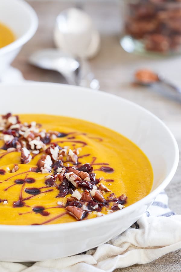 Kabocha Squash Soup topped with nuts in a white bowl.