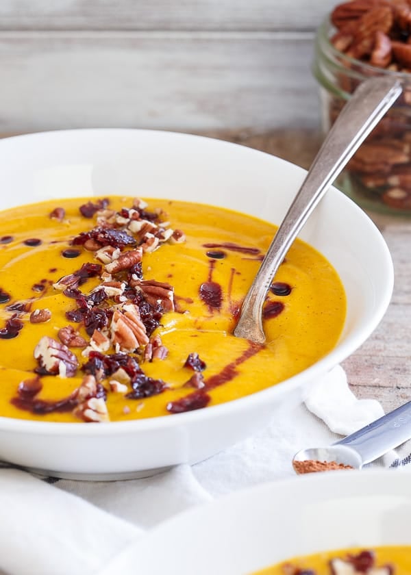 Fall Kabocha Squash Soup in a white bowl with a spoon.