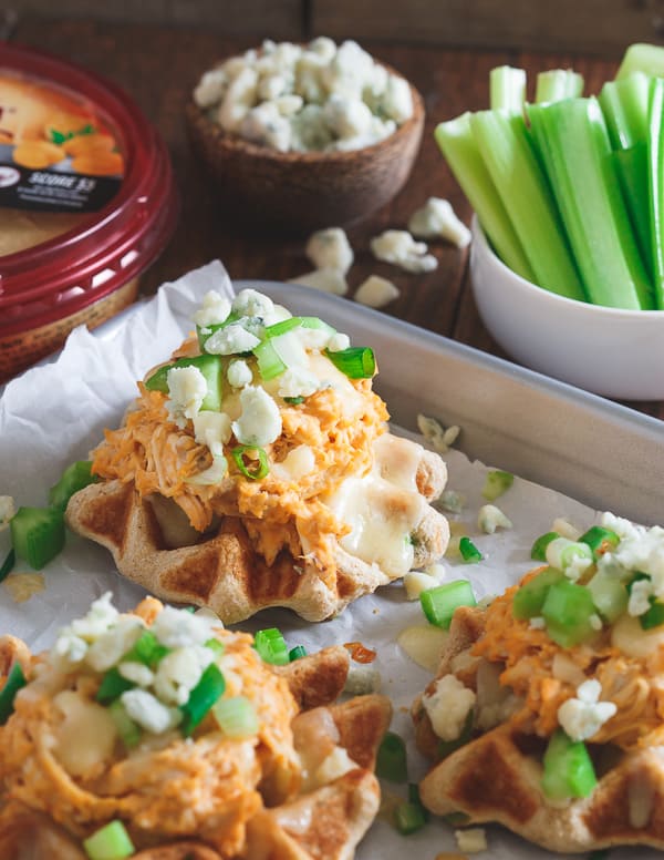 These buffalo hummus chicken waffle bites have sharp melted cheddar, blue cheese crumbles and crunchy chopped celery on top!