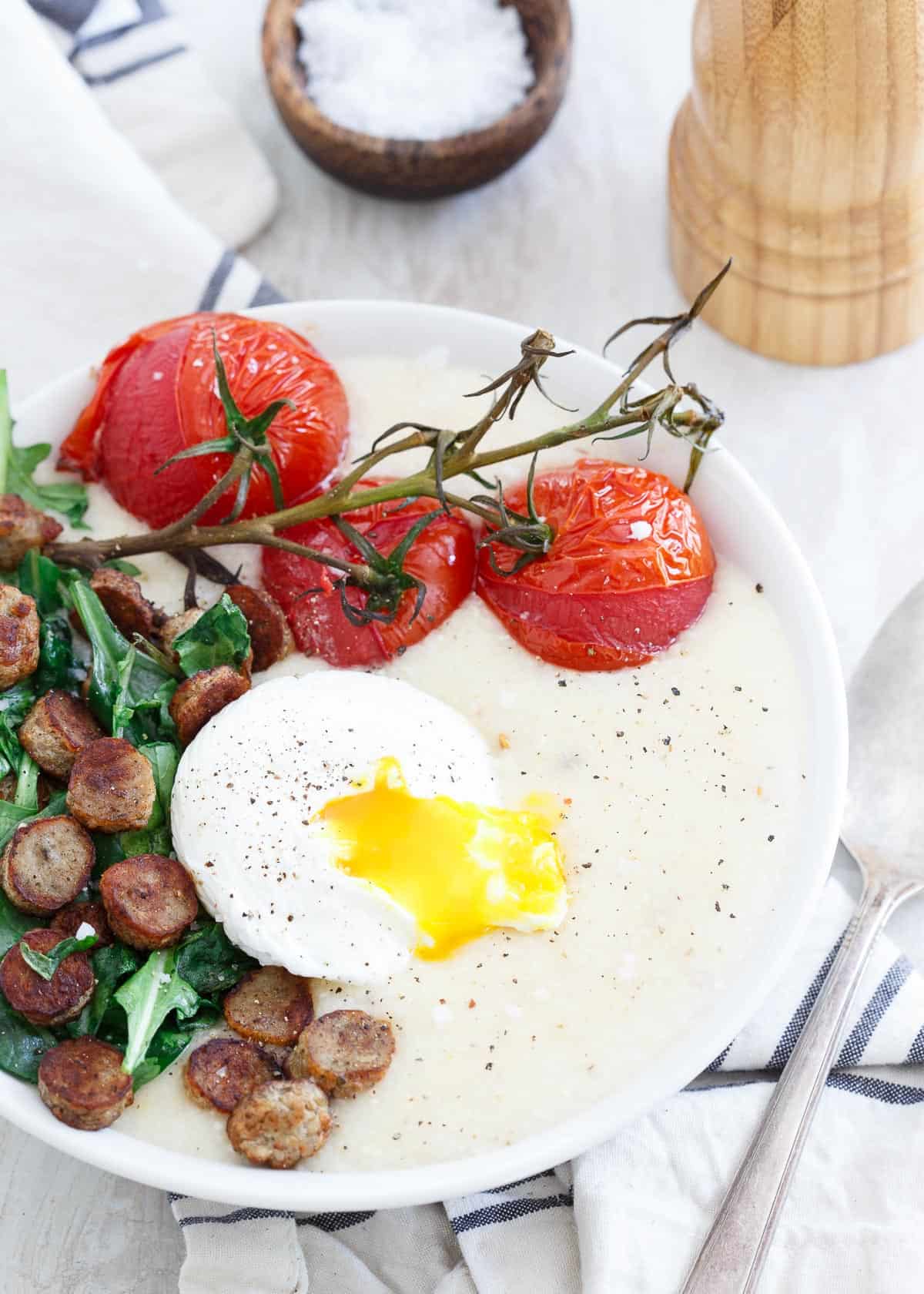 These cheddar cheese grits are topped with a chicken sausage baby greens sauté, oven burst vine ripe tomatoes and a perfectly poached runny egg.