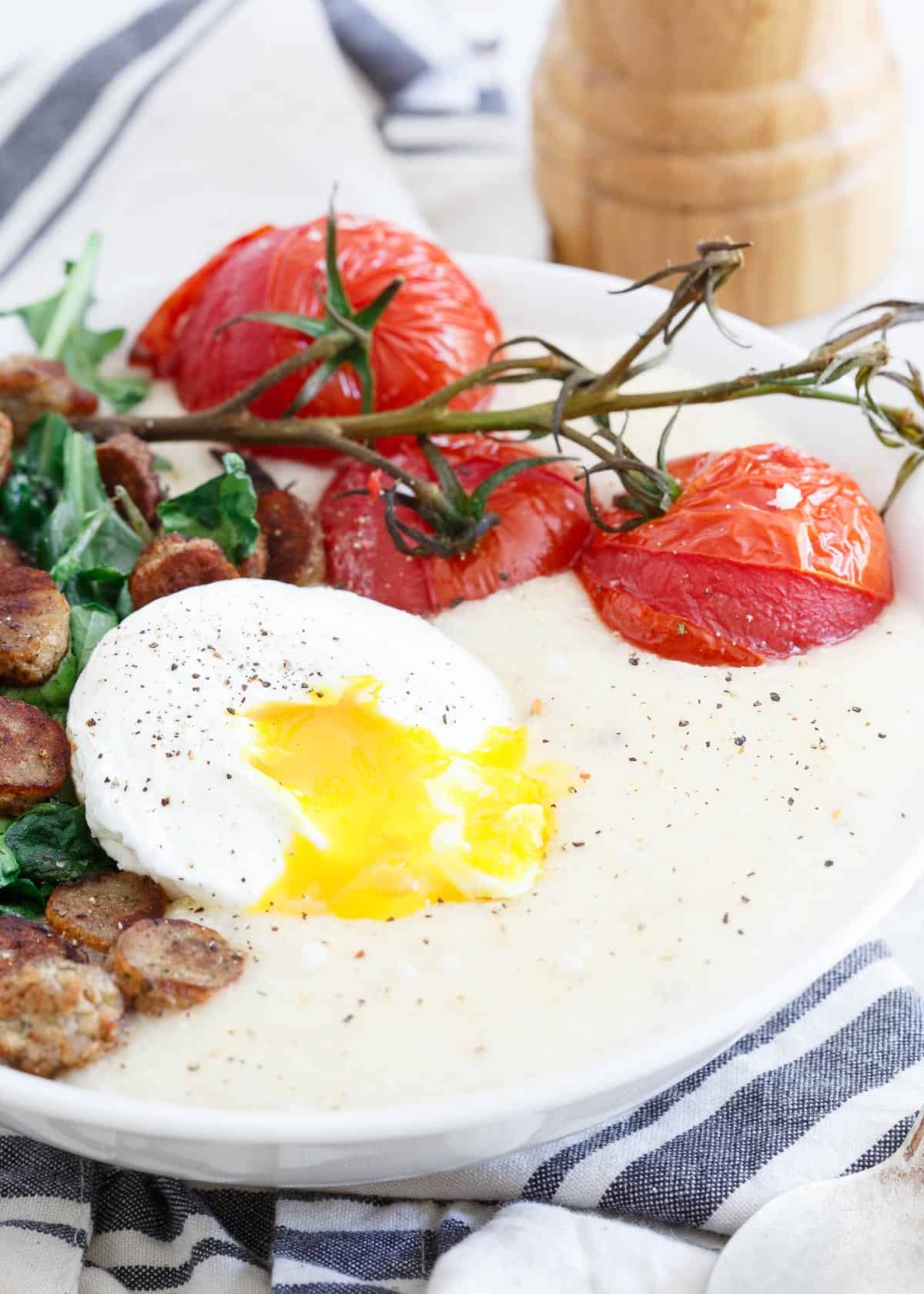 Chicken Sausage Cheese Grits with Burst Tomatoes and a runny poached egg are an easy brinner option for hectic weeknights.