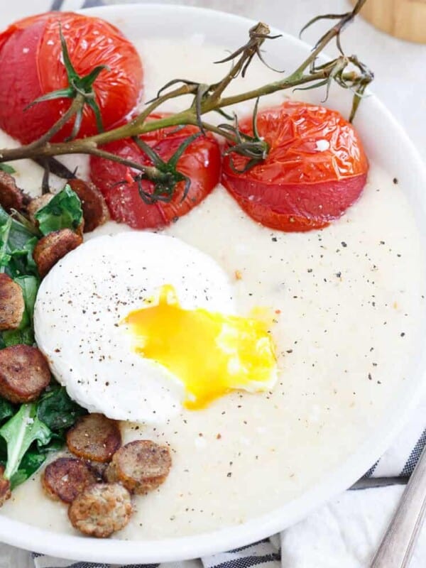These cheddar cheese grits are topped with a chicken sausage baby greens sauté, oven burst vine ripe tomatoes and a perfectly poached runny egg.