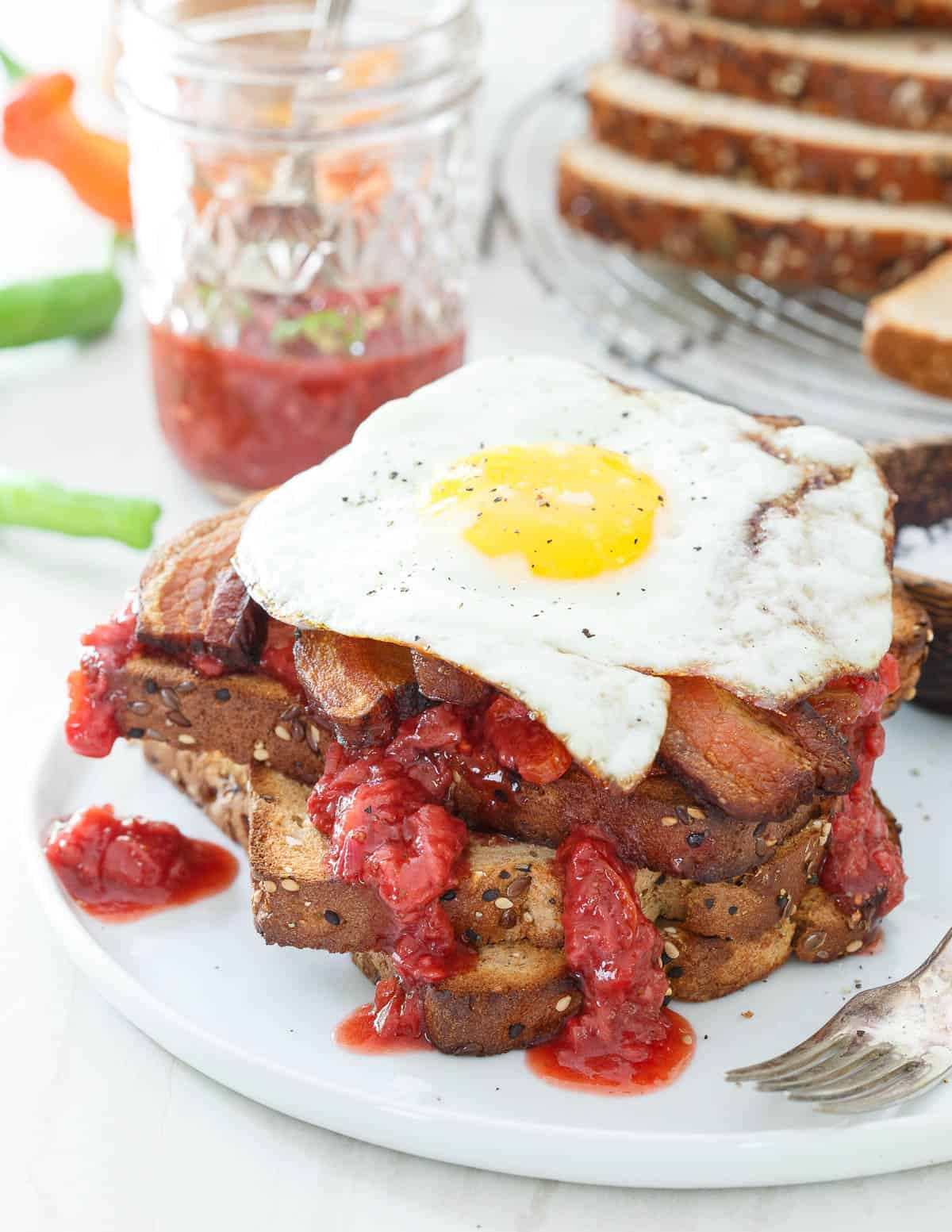 An easy strawberry chile jam is slathered on thick and hearty toasted bread with crispy cooked bacon and a fried egg for the ultimate breakfast sandwich.