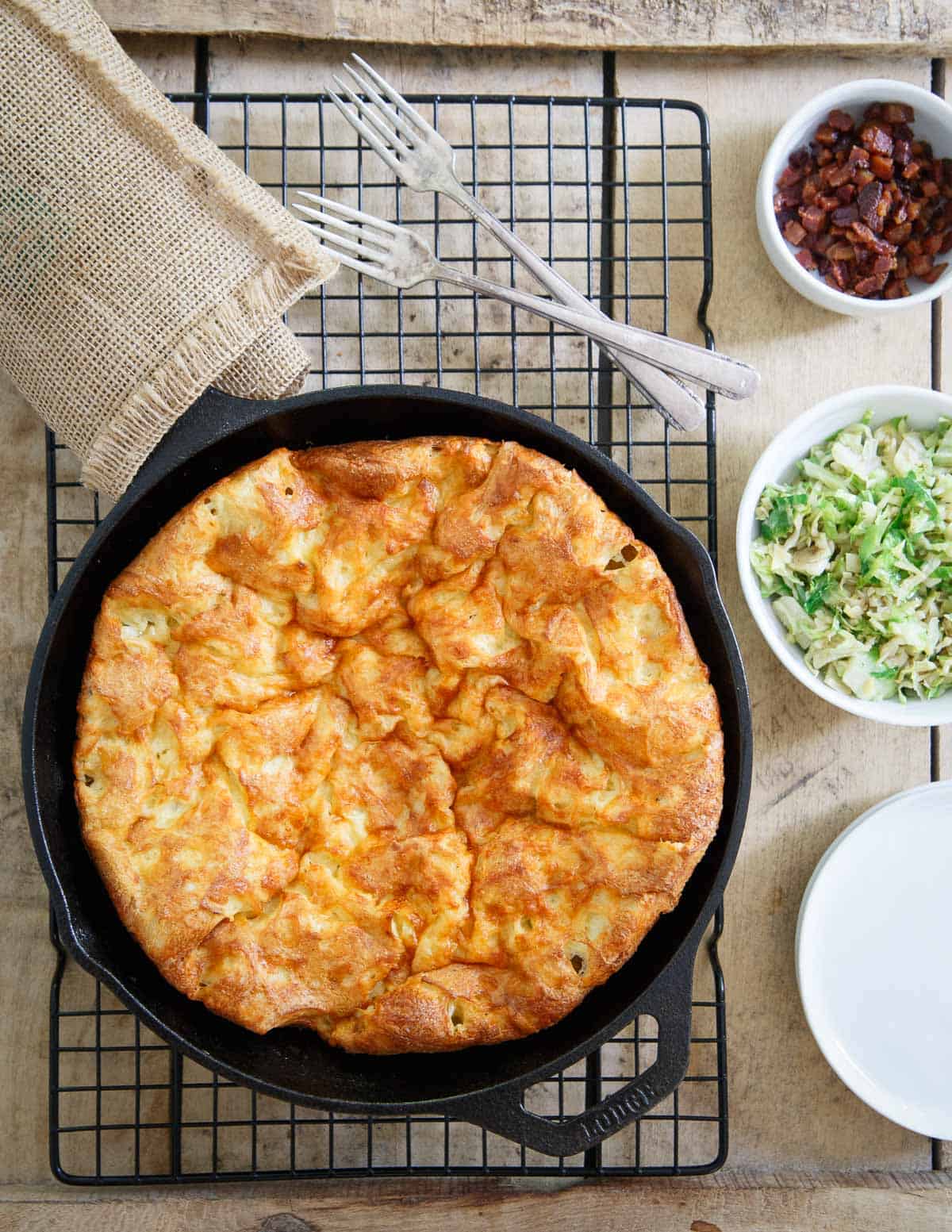 A savory Cheddar Dutch Baby gets topped with bacon and brussels for an easy dinner or brunch.