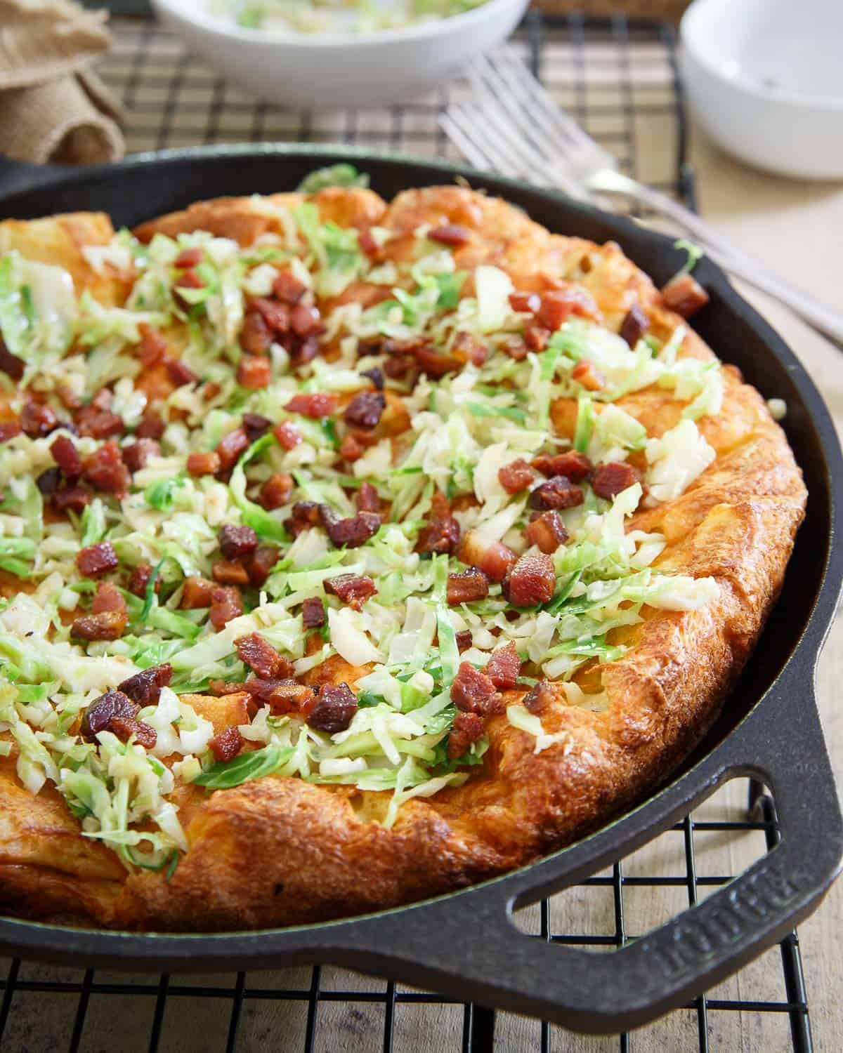 This cheddar Dutch baby is topped with crispy bacon and sautéed brussels sprouts for a savory take on the classic Dutch pancake.