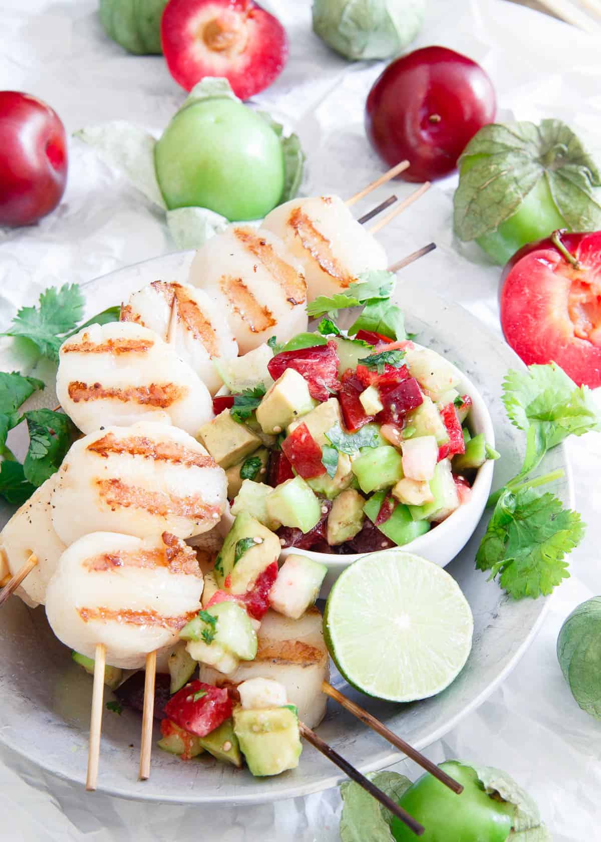 These grilled scallops are simply prepared and topped with a fresh summery tomatillo plum salsa for a delicious light meal.