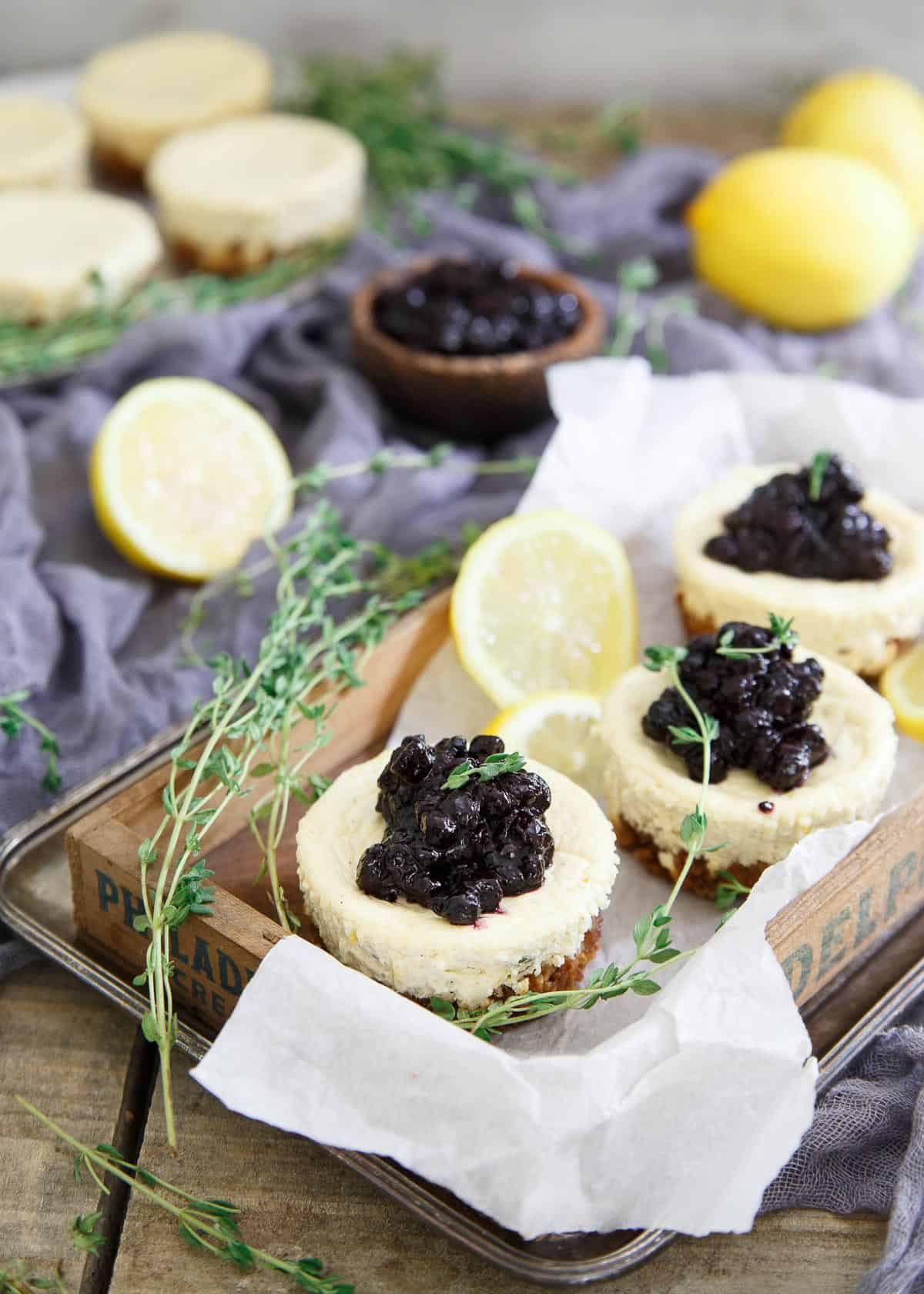 These gluten free granola crust mini cheesecakes are infused with lemon and thyme and topped with a quick blueberry thyme compote.