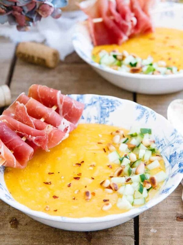 This chilled mango melon soup is garnished with tangy pickled cucumber and prosciutto skewers for a salty, sweet and cool summer dish.